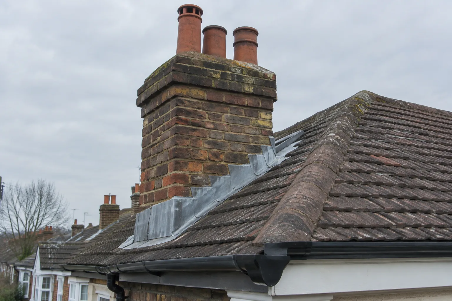Roof corner showing chimney flashing, tiles and guttering